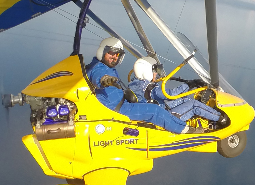 Happy student waving hi while flying above Lake Tahoe in powered hang glider.